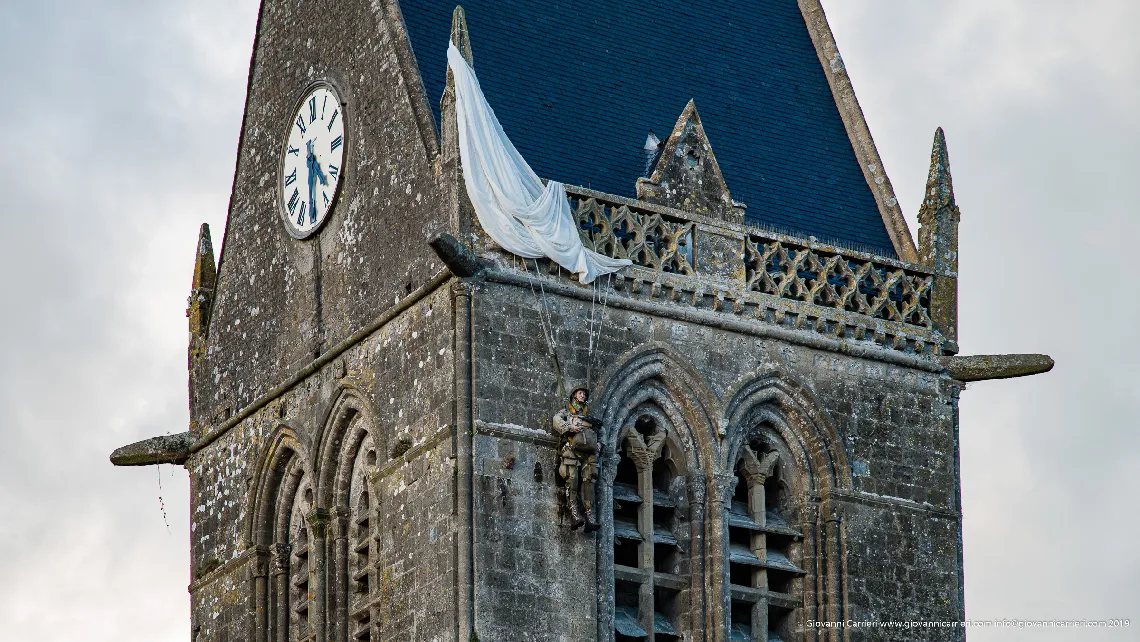 Il campanile della chiesa, con il monumento al paracadutista a Sainte Mère Église