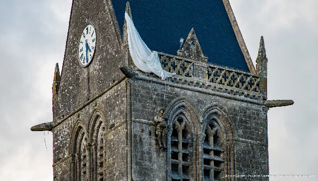 The bell tower of the church, with the monument to the parachutist in Sainte Mère Église
