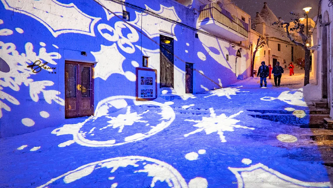 The colored lights illuminate the historic center of Alberobello