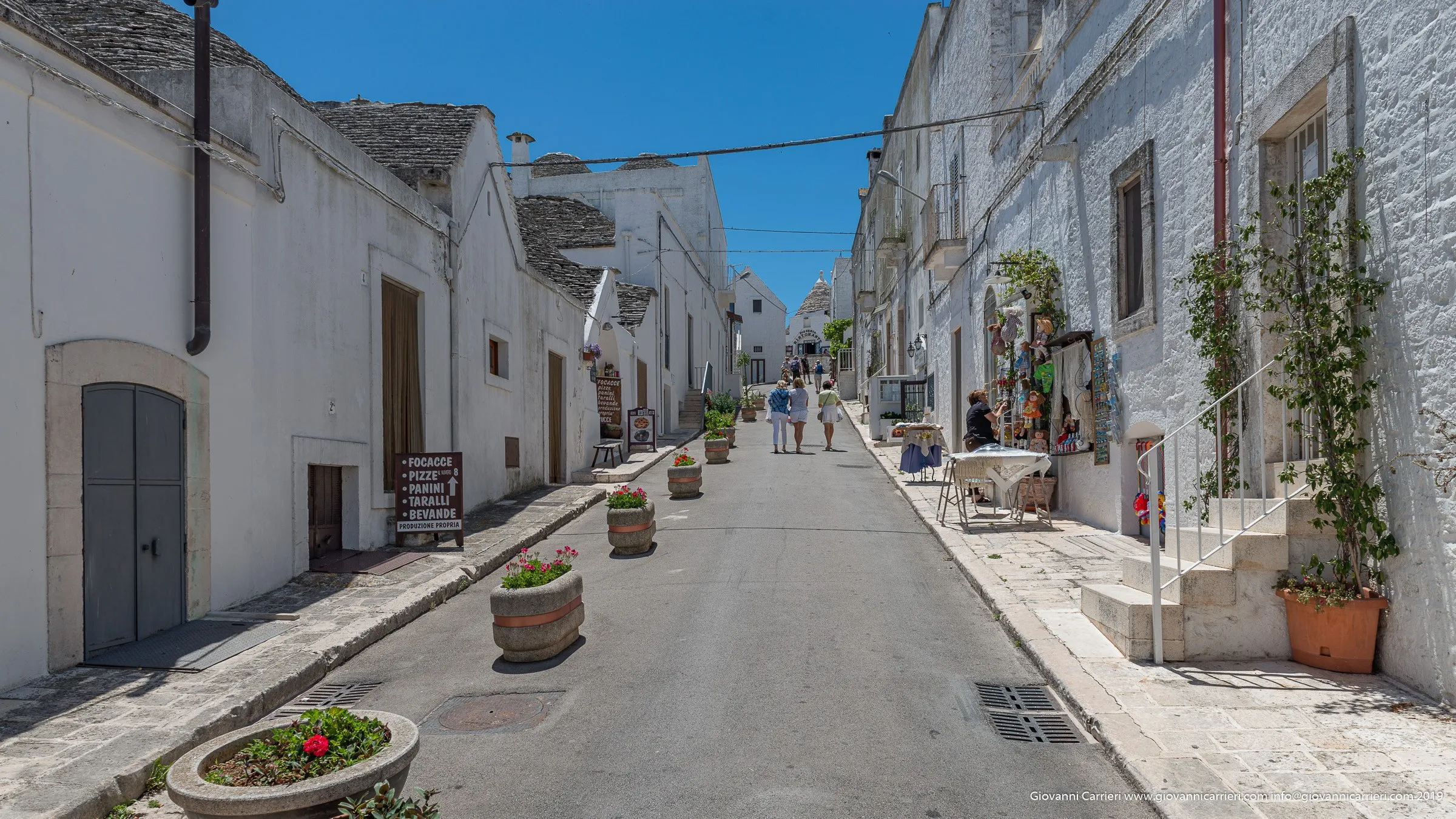 Tourists walking among the Trulli of Alberobello - Apulia