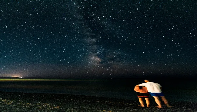 A couple contemplates the Milky Way on the Crete coast