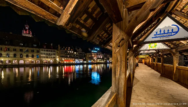 Vista notturna dall'interno del ponte Kapellbrücke del fiume Reuss e dell'antica città di Lucerna