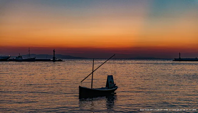 Sunset over Chora harbor with fishing boat