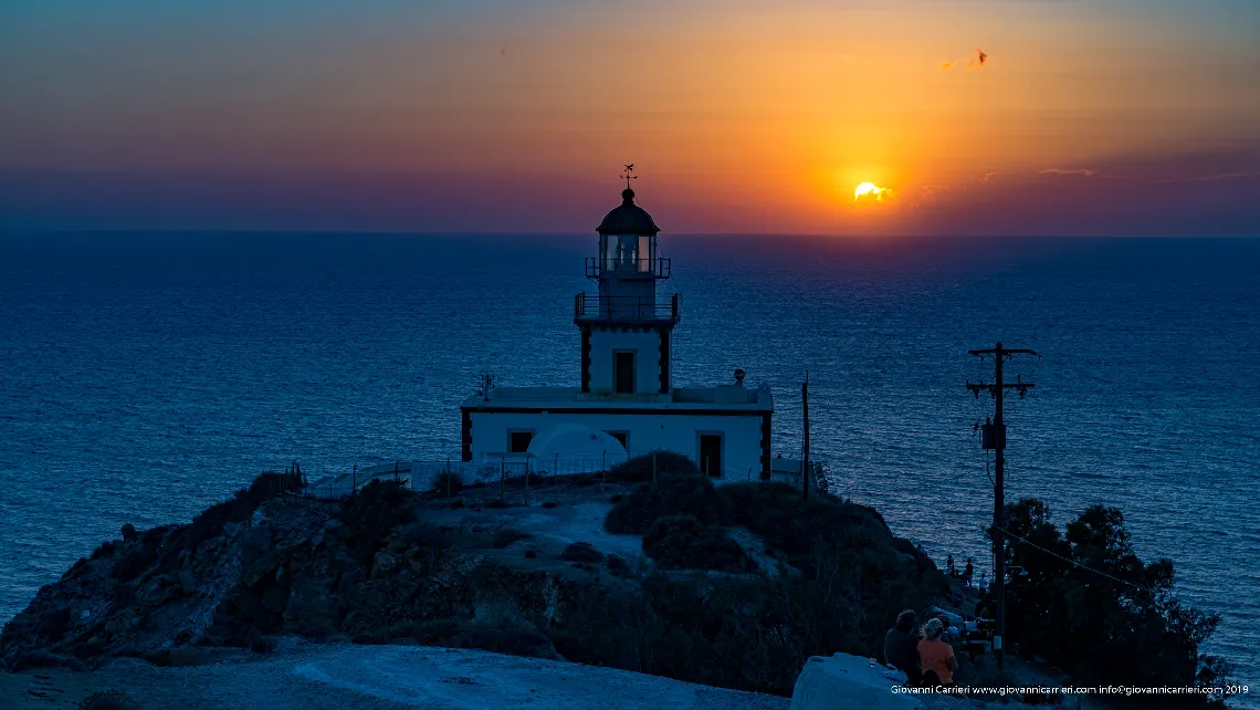 Il tramonto abbaglia il faro di Santorini